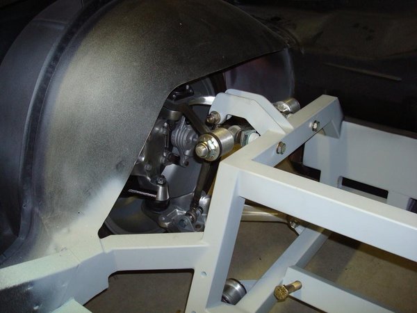 Front suspension showing strut rod and revised wheel house opening on trunk side.