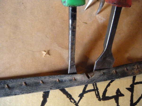 I couldn't do this while taking the picture, but while easing the metal strip back, holding both prybars with one hand, I used a small angled pliers to hold and feed the nail through the hole.